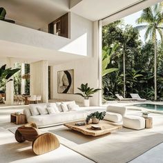 a living room filled with white furniture next to a swimming pool and palm trees in the background