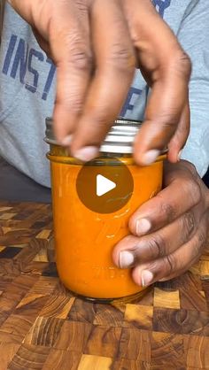 a person is holding a jar with something in it on a wooden counter top,