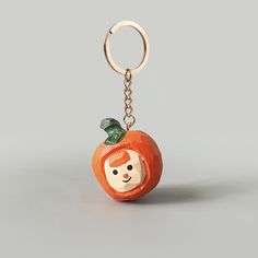 an orange shaped keychain with a face on it's front and side