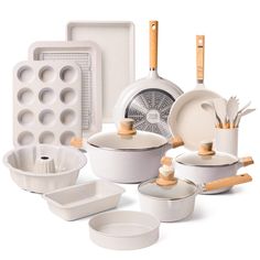 an assortment of white dishes and pans with wooden utensils on the side