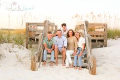 a family sitting on a wooden bench in the sand