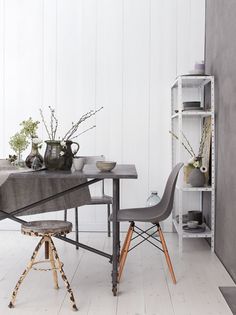 a dining table with two chairs next to it and a shelf full of vases