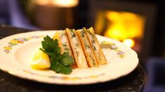 a white plate topped with four sandwiches next to a slice of lemon and parsley