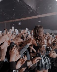 a group of people holding up their cell phones in front of a stage with microphones