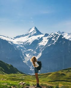 a woman standing on top of a lush green hillside