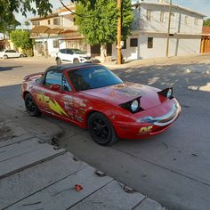 a red sports car parked on the side of the road in front of a house