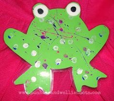 a green frog sitting on top of a pink shirt covered in confetti and sprinkles