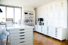 a white kitchen with lots of drawers and shelves on the wall next to a large window