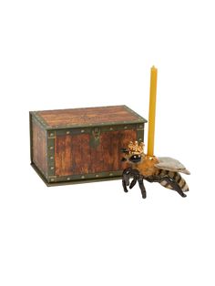 a wooden box with a bee figurine next to it and a yellow candle