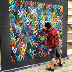 a man is painting hearts on the side of a building with spray paint and wood planks