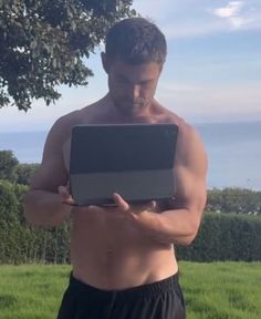 a shirtless man holding a laptop in his hands