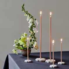 candles are arranged on a table with flowers and greenery