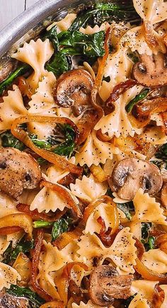 a pan filled with pasta, mushrooms and spinach