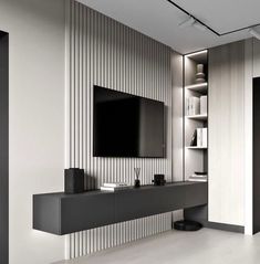 a modern living room with white walls and black entertainment center on the wall, built in bookshelves