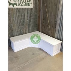 a white bench sitting in front of a metal wall with a green sticker on it