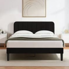 a white bed with black headboard and foot board in a room next to a painting on the wall