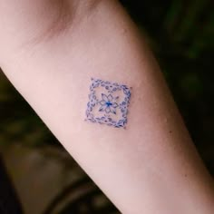 a small blue and white tattoo on the arm