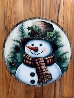 a wooden plaque with a snowman wearing a hat and scarf