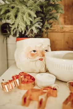 a ceramic santa clause sitting on top of a counter next to a potted plant