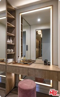 a dressing table with a mirror and stool in front of it that is lit up