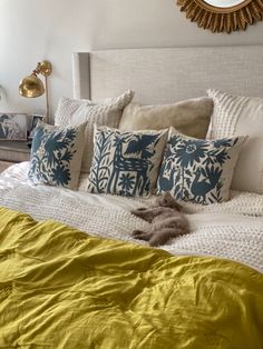 a bed with yellow and blue pillows on top of it next to a gold headboard