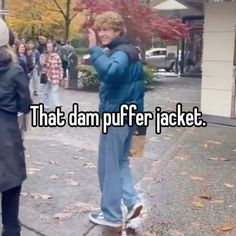 a person standing on the sidewalk with their hand up in the air and text that says, that dam puffer jacket