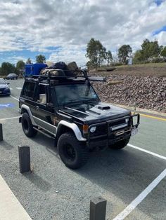 an suv is parked on the side of the road with its roof up and luggage strapped to it