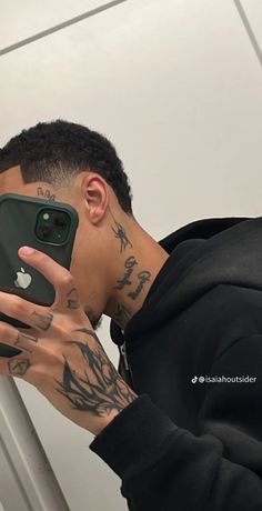 a man taking a selfie with his cell phone in front of him and tattoos on his arm