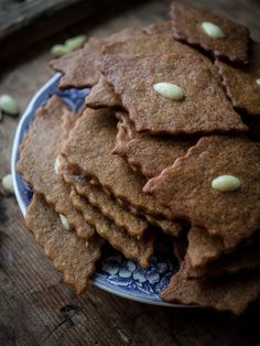 a blue and white plate topped with cookies on top of a wooden table next to nuts