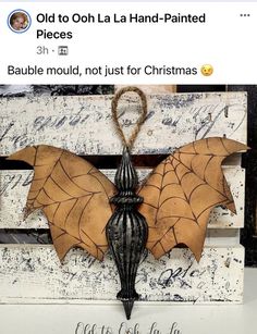 a bat hanging from a light fixture on top of a wooden box with writing underneath it