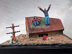 two people standing on top of a roof with their arms in the air and one holding his hands up