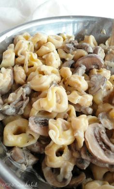 a metal bowl filled with pasta and mushrooms