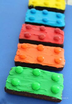 lego themed cookies are arranged in the shape of a train track with green, orange and blue frosting