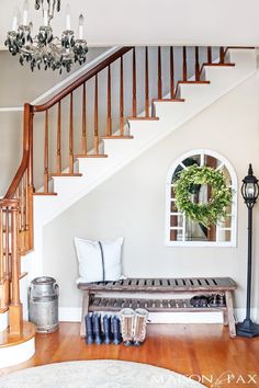 a living room filled with furniture and a chandelier hanging from the ceiling next to a staircase