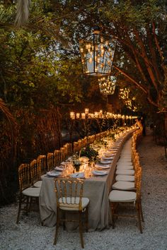 a long table is set up with candles and place settings for an outdoor dinner party