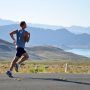 a man running down the road with mountains in the background