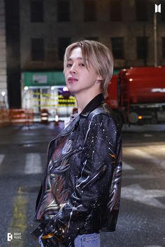 a young man standing in the middle of an empty street at night with his hand on his hip