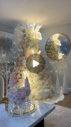 a christmas tree with lights and decorations in the corner next to a mirror on top of a table