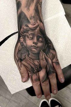 a person's hand with a tattoo on it that has a praying girl in the middle