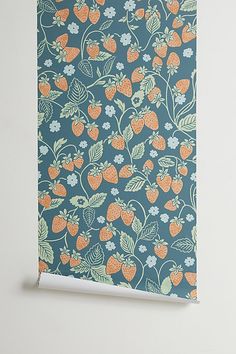 a blue wallpaper with strawberries and flowers on it, next to a white wall