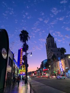 a city street with palm trees and neon signs