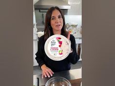 a woman holding up a plate with fruit on it in front of a counter top