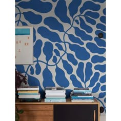 a blue and white wall with books on it next to a desk in front of a painting