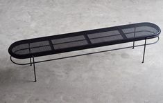 a black bench sitting on top of a cement floor next to a metal frame structure