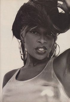 a black and white photo of a woman with large hoop earrings on her head, wearing a tank top