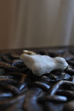 a ring sitting on top of a piece of black leather with a white stone in the middle