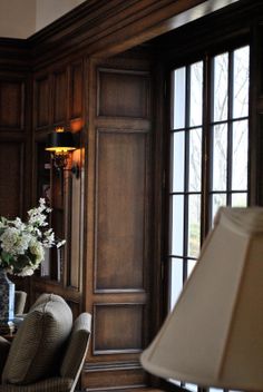 a living room with wood paneling and a lamp on the table in front of it