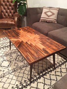 a wooden table sitting on top of a rug in front of a brown couch and chair