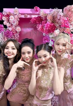 the girls are posing in front of pink flowers and holding their hands up to their ears