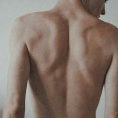 the back of a man with no shirt on standing in front of a white wall